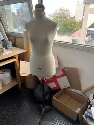 a mannequin on a stand in a room with a lot of boxes on the floor