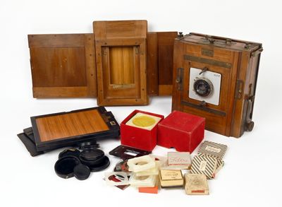 un ensemble d'appareils photo anciens et d'autres objets posés sur une surface blanche
