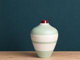 un vase vert posé sur une table en bois, près d'un mur bleu