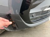 a person holding a measuring tape on the front of a car