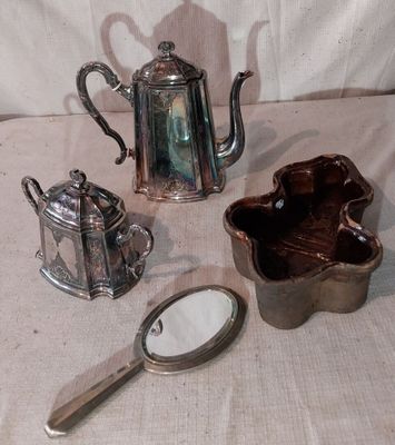 une théière en argent, une théière en argent et un miroir posé sur une table