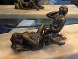 une statue en bronze représentant un homme et une femme assis sur un banc