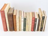 several old books are lined up in a row on a white surface