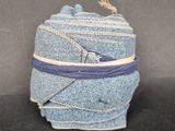 une photo d'un rouleau de jeans bleus enveloppé dans un ruban violet