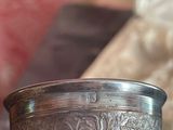 a silver cup sitting on a table next to a pillow