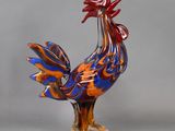 a glass sculpture of a rooster with a red and blue tail