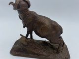 statue of a ram standing on a rock on a white surface