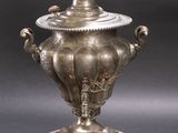 silver plated urn with lid on stand on grey background