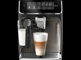 the coffee machine has a glass of milk in front of it