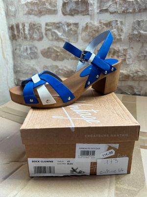 blue and white high heeled sandals in a box on a table