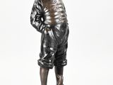 statue of a boy with a hat on his head standing on a base