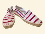 pair of red and white striped espadrills on a beige background