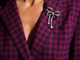 the woman is wearing a red and black checkered shirt and a bow brooch