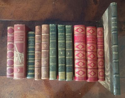several old books are lined up on a shelf on a table