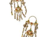 a pair of earrings with gold and green stones