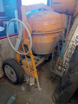 a cement mixer sitting in a garage next to a pile of tires