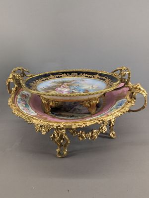 an ornately decorated bowl on a stand on a gray surface