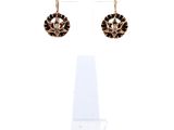 une paire de boucles d'oreilles noires et dorées présentée sur un présentoir transparent