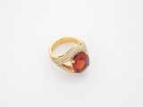 a yellow gold ring with a red stone and diamonds