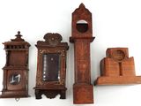 trois horloges en bois et un support d'horloge posés sur une surface blanche