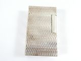 une image représentant un étui à cigarettes argenté posé sur une surface blanche