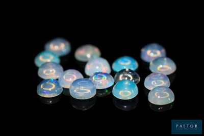 some white oplite beads are arranged in a row on a black surface