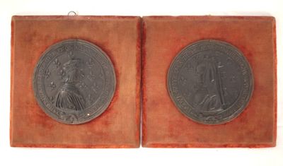 two silver medallions of a lady and a man in a red velvet case