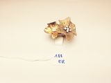 an image of a gold flower broochle on a white surface