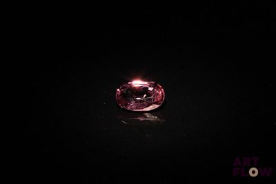 a close up of a pink diamond on a black surface