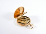 a gold pocket watch sitting on a white surface