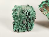 two pieces of green and black mineral on a white surface