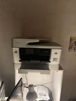 une imprimante posée sur un bureau, à côté d'une lampe