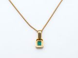 a gold necklace with an emerald stone on a chain