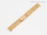 a close up of a gold bracelet on a white surface
