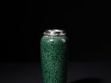 a green vase that is sitting on a black surface