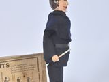 toy soldier in uniform standing next to a cardboard box with a sign on it