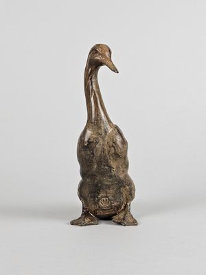 sculpture en bronze représentant un canard debout sur ses pattes arrière, posée sur une surface blanche