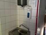 une salle de bains équipée d'un lavabo et d'un sèche-mains fixé au mur