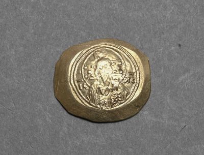 a close up of a gold coin with a face on it
