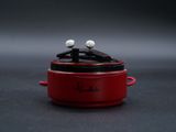 un petit pot rouge contenant deux boules blanches