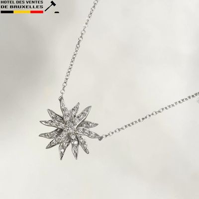 a silver necklace with a starburst pendant on it