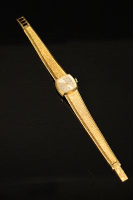 a gold watch on a black surface with a black background
