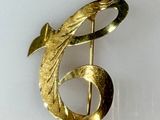 a gold brooch with a fish on it on a white surface