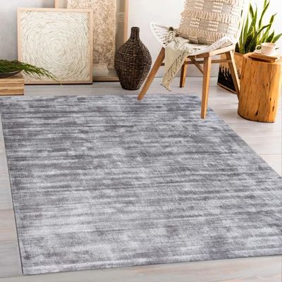 a grey rug in a living room with a chair and potted plant