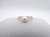 a white pearl ring sitting on top of a white cushion