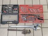 une trousse à outils posée sur un sol carrelé, à côté d'une boîte à outils