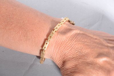 someone is wearing a gold bracelet with a chain on it