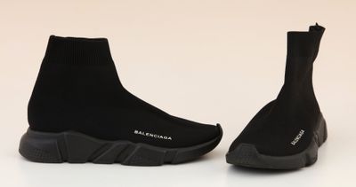 a pair of black sneakers with black soles on a white surface