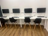 four computers are sitting on a white desk with black chairs