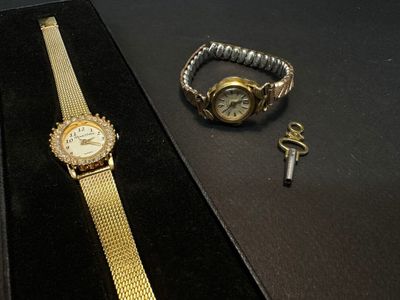 a gold watch and a key on a black table
